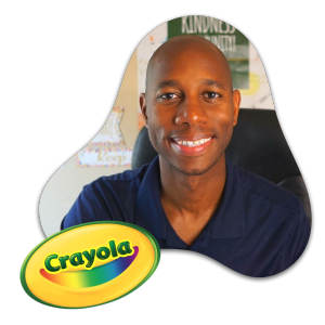 A smiling man in a navy shirt sits indoors, with a Crayola logo in the corner and posters behind him, reflecting leadership strategies in arts integration.